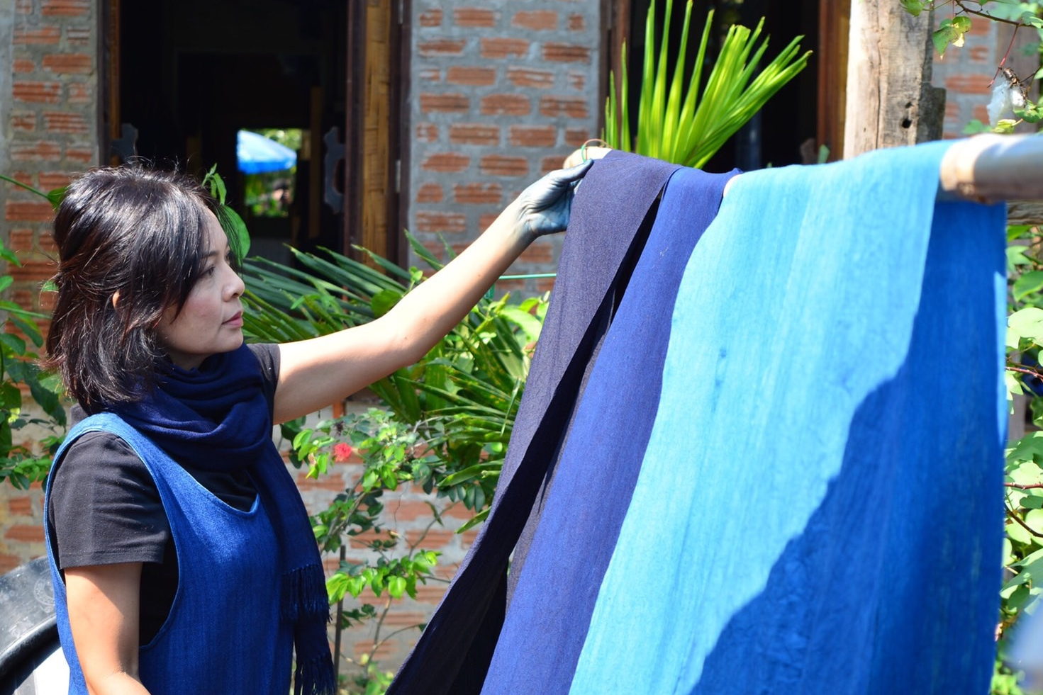 Sakuna Saranan, founder of KRAMSAKON, hanging naturally dyed indigo cloth to dry