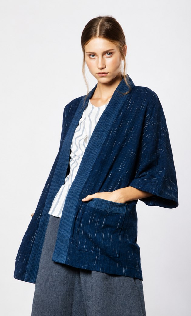 A model wearing an indigo-dyed jacket over a white shirt