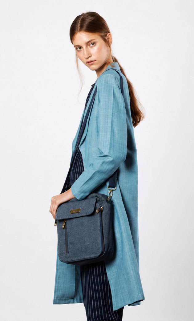 A model wearing a long indigo-dyed coat with a shoulder bag